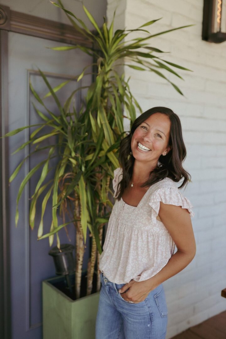 A woman standing next to a plant outside.