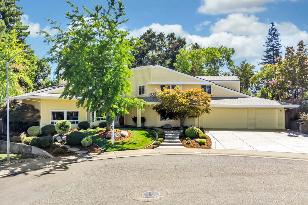 A large yellow house with trees in the front yard.