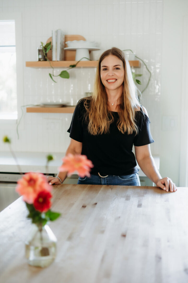 A woman sitting at the table with flowers in front of her.