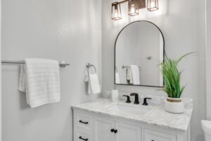 A bathroom with white walls and marble counter tops.